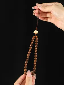 Gros plan d'un bijou de téléphone en perles de santal avec une fleur de lotus sculptée