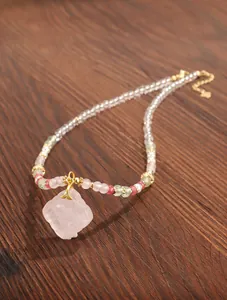 Close-up of a handcrafted beaded necklace with a carved rose quartz flower pendant
