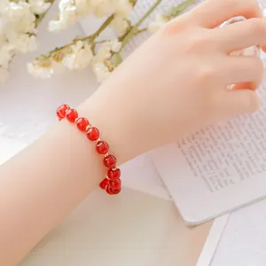 Elegant red strawberry crystal beaded bracelet with gold accents worn on a lady's wrist