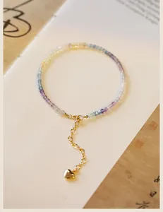 Detailed macro view of 2mm rainbow fluorite bead bracelet with 14k gold heart charm