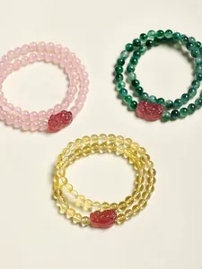 Vue détaillée de bracelets double rang en perles de cristal naturel, rose, vert et jaune.