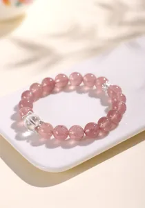 Elegant detail of a strawberry quartz and white crystal beaded bracelet on a white tray.