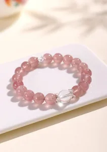 Close-up view of strawberry quartz and white quartz beaded bracelet with silver charms