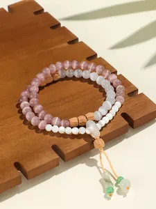Detalle de pulsera de doble capa de ojo de gato con cuentas de sándalo y dije de jade.