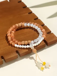 Detalle macro de una pulsera de doble hilo con cuentas de ojo de gato rosa y colgante de dona