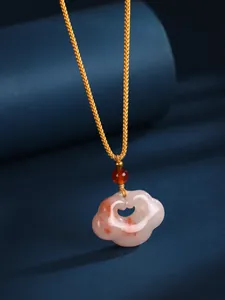 Close-up of Chinese style cloud jade pendant with carnelian bead and gold cord