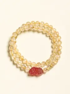 Détail d'un bracelet double rang en quartz rutilé doré et pierre rouge sculptée