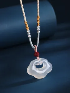 Close-up of white agate Ruyi lock pendant with silver beads and woven cord.