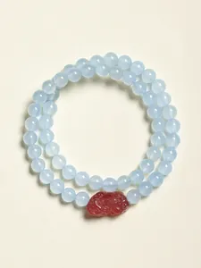 Détail d'un bracelet double rang en perles bleues avec pendentif en cristal fraise