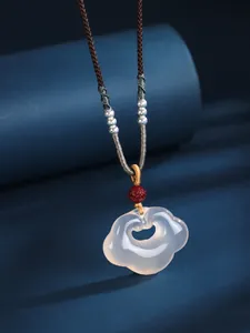 Macro view of white agate Xiangyun Ruyi lock pendant with silver beads and brown cord