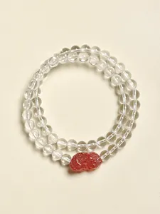 Gros plan d'un bracelet à double rangée avec un pendentif en quartz fraise sculpté.