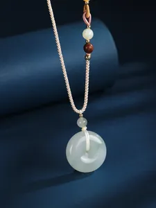 Close-up of a semi-transparent white jade donut pendant on a beige woven cord necklace