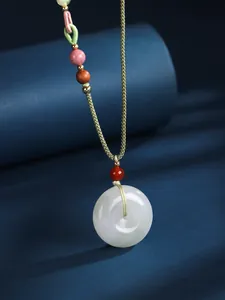 Close-up view of a polished white jade circular pendant on a green woven cord