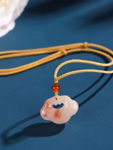 Macro view of Chinese style cloud Ruyi lock pendant with pink jade and golden woven cord