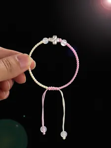 Vue détaillée d'un bracelet tressé rose et blanc fait main avec trèfle en argent pur