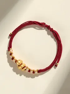 Gros plan d'un bracelet en corde rouge tressée à la main avec trois breloques serpent dorées.
