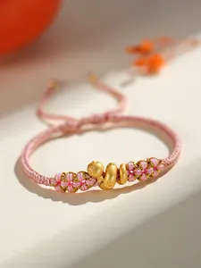 Détail d'un bracelet de l'année du serpent tressé à la main avec des nœuds dorés roses