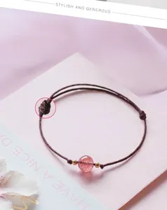 Close-up of a handcrafted woven rope bracelet featuring a single pink strawberry quartz bead.