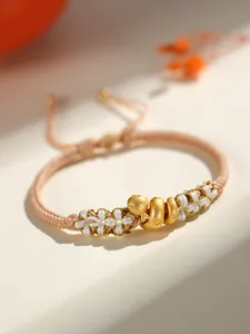 Vue détaillée d'un bracelet tissé à la main avec un charm de serpent doré et fleurs.