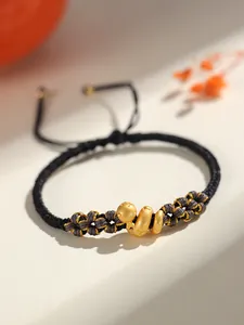 Vue macro d'un bracelet noir et or tressé à la main avec une adorable breloque serpent dorée
