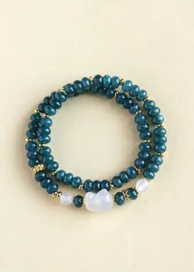 Macro view of double-strand teal chalcedony beaded bracelet featuring a white fox charm.