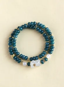 Close-up of a double-strand beaded bracelet with dark green beads and a white fox charm.