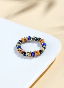 Macro view of lapis lazuli and black agate beaded ring on a white ceramic surface.