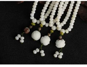 Close-up of white Bodhi root 108 prayer beads with intricately carved lotus pendants.