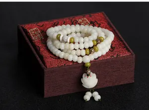 Macro detail of 108 Bodhi root beads prayer bracelet with carved white lotus pendant