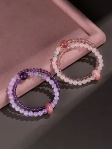 Detailed close-up of double-strand amethyst and rose quartz beaded bracelets with charms
