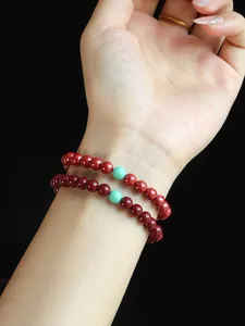 Close-up of 4mm red cinnabar beaded bracelets featuring a green turquoise accent bead.