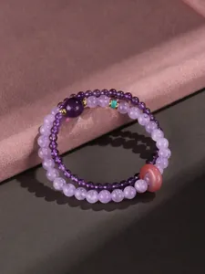 Close-up of double-strand amethyst and aquamarine beaded bracelet with pink donut charm