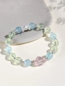 Macro view of 8mm aquamarine and prehnite beaded bracelet with a central pink crystal