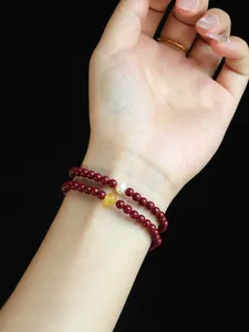 Detail view of double-layer cinnabar bracelet with freshwater pearl and yellow bead