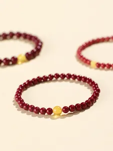 Close-up of deep red cinnabar beaded bracelets with yellow amber bead on cream base
