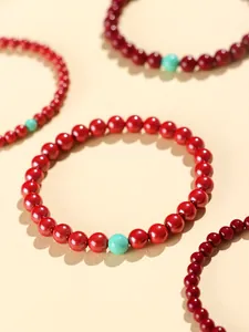 Macro view showing the glossy texture of cinnabar red beads with a turquoise accent
