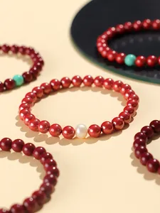 Close-up of red cinnabar bracelet featuring a white freshwater pearl accent