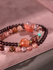 Macro detail of a double-layer beaded bracelet featuring strawberry quartz and garnet stones