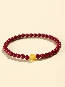 Detail showing deep red cinnabar beads with a single translucent yellow lucky bead bracelet.