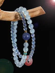 Close-up of aquamarine and amethyst beaded bracelet with a pink stone donut charm.