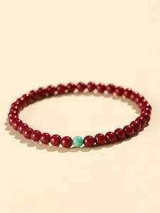 Close-up of 4mm red cinnabar beads bracelet with single turquoise stone detail.