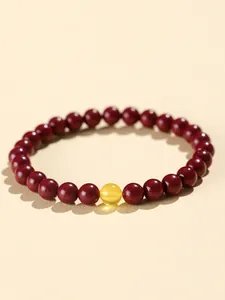 Detail view of red cinnabar beaded bracelet with a single amber-like yellow bead.