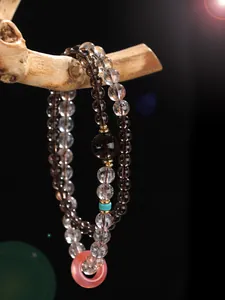 Detailed macro shot of double-strand crystal bead bracelet with pink donut pendant