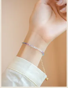 Close-up of ultra-thin 2mm rainbow fluorite beaded bracelet on wrist with gold chain