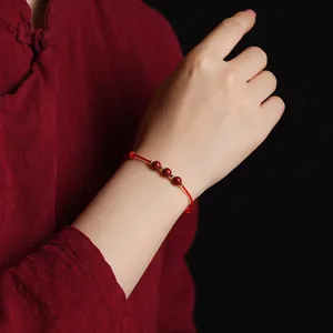Gros plan d'un bracelet en fil rouge traditionnel avec des perles de cinabre au poignet