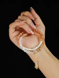 Primer plano de una pulsera de dos vueltas con cuentas de ojo de gato rosa y madera fina.