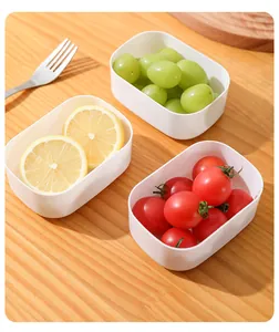 Detail view of small white food prep containers holding fresh fruits on wooden table