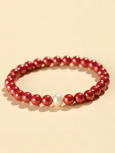 Macro view of cinnabar beads and a natural freshwater pearl on this lucky bracelet