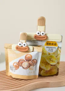 Cartoon-faced food bag sealing clips shown in use on snack packaging over wooden base