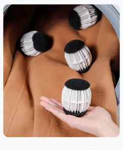Detail shot of white anti-tangling laundry balls with black sponge ends on brown coat